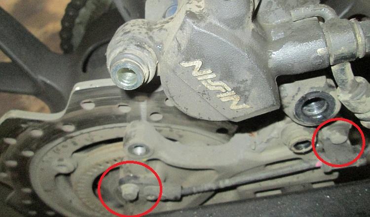 The ABS sensor on the brake hanger with the retaining bolts circled in red