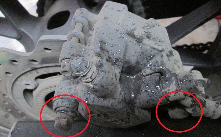 The rear calliper with the 2 bolts that need to be removed circled in red