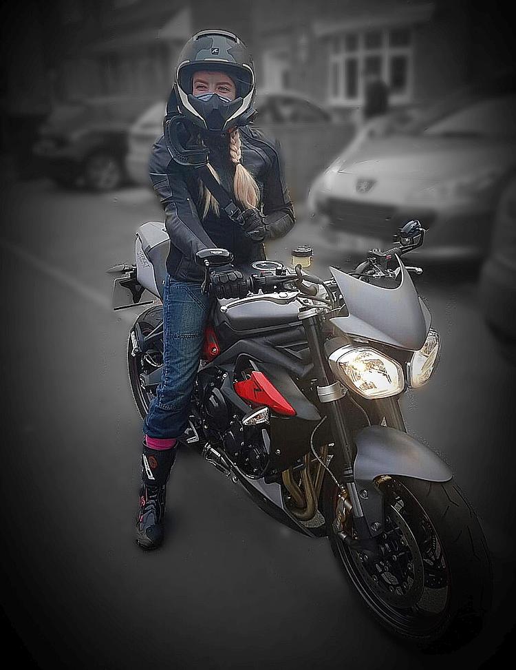 Jade sat on her Triumph Street Triple smiling with her helmet on