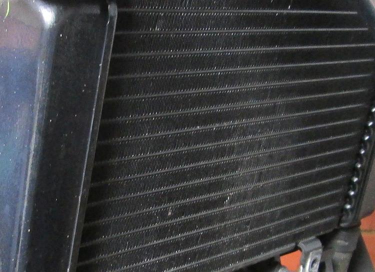 The radiator of a motorcycle with no cover on, naked