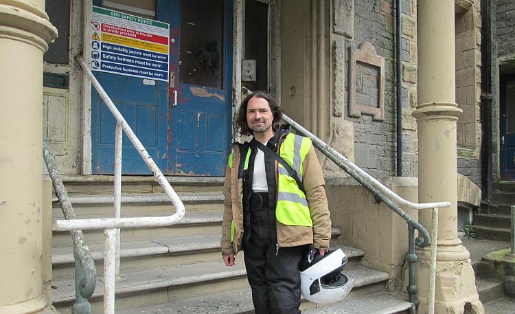Ren stands in his bike gear on the steps of the set of the police station in Hinterland