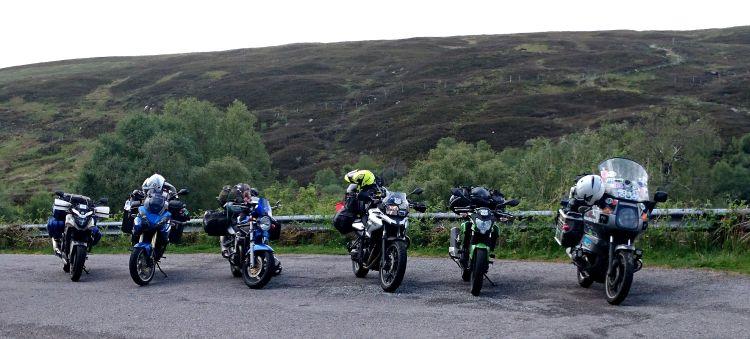 Various motorcycles lined up against the rugged Scottish backdrop