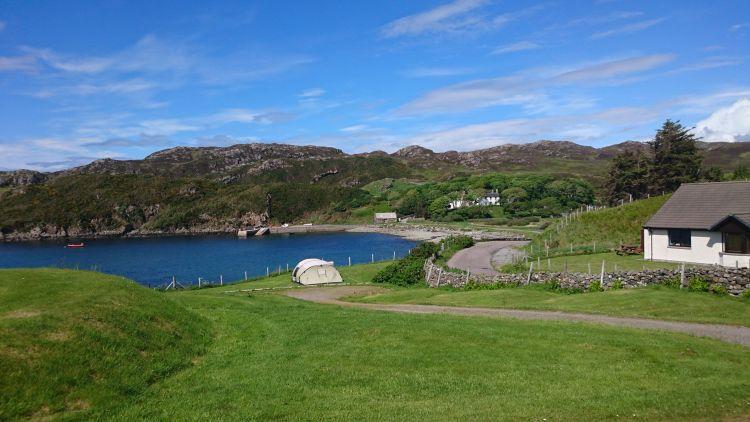 Rocky hillsides, deep blue sea and lush green grasses at Scourie Bay