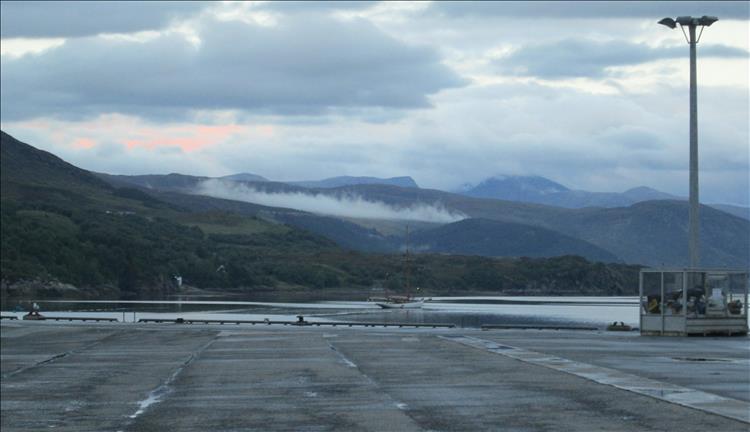 Highland hills and mountains run down to Loch broom in the dark evening skies