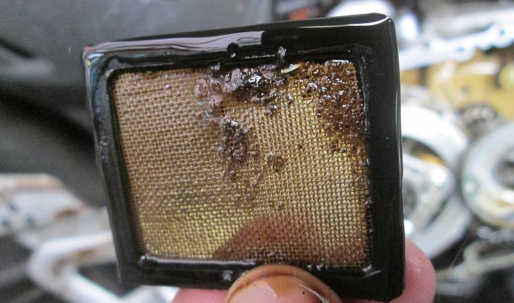 The gauze oil filter has a little dirt and muck on it and one sliver of shiny metal