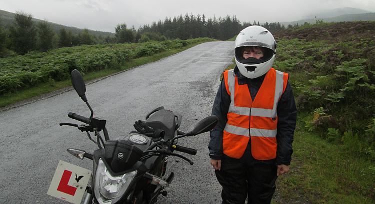 Sharon stands by her 125 with L plates in the rain of Scotland