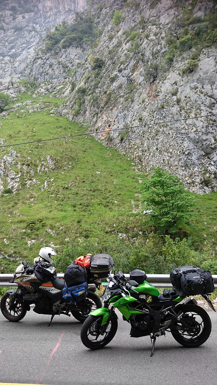 The 2 motorcycles with the steep rocky expanse of the mountains rising up behind