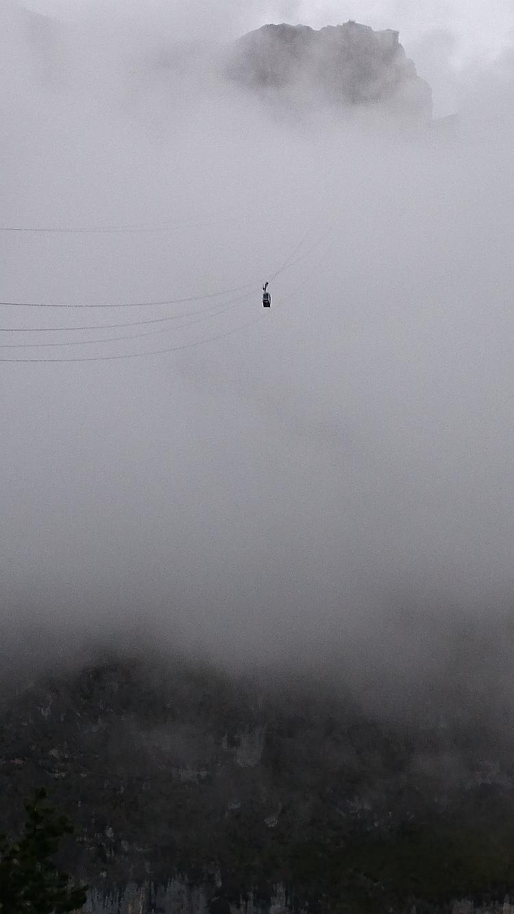 A cable car gondola can be seen disappearing into the clouds at Fuenta De