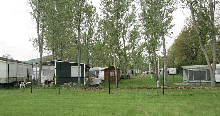 An ordinary field with trees and caravans and some small outbuildings