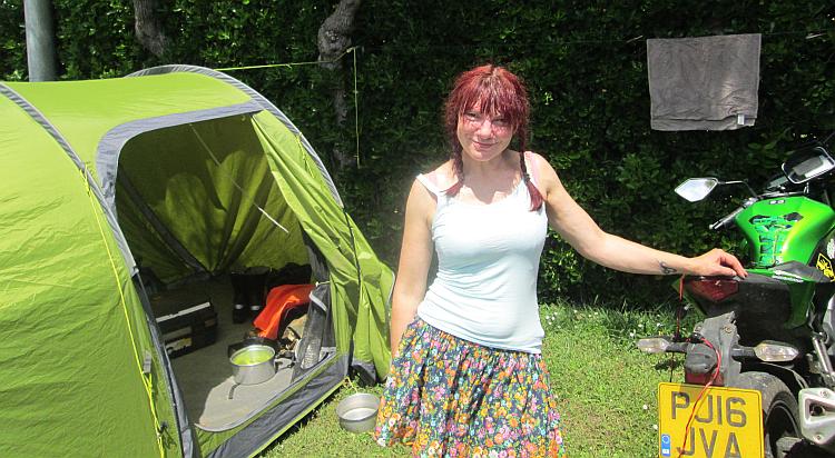 Sharon in the sun posing with the bikes and tent and actually wearing a skirt