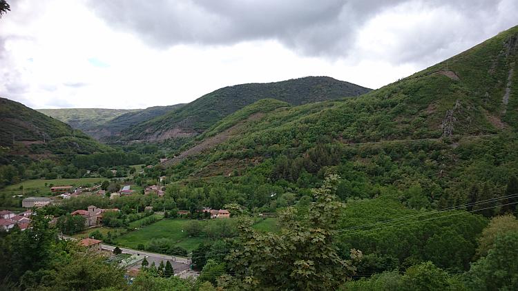 A tiny Spanish village nestling in the bottom of a vast steep lush green valley