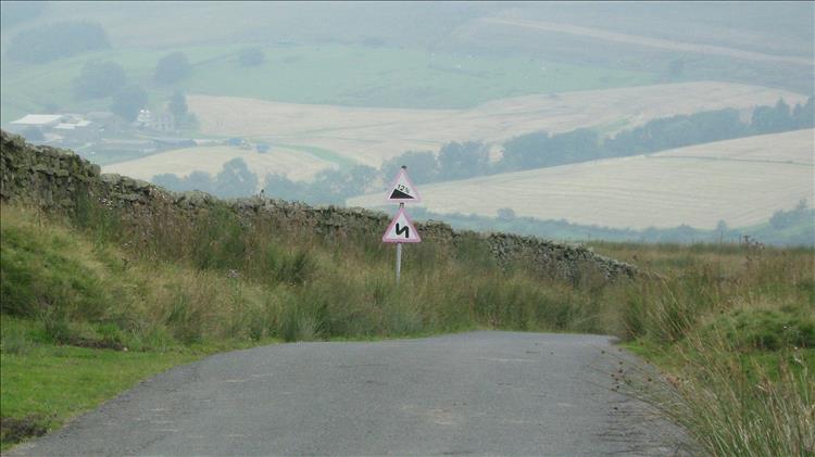 Road signs showing steep road and sharp bends on a countryside lane in Lancashire