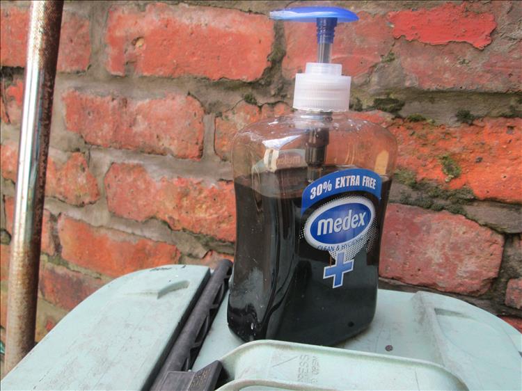 A used hand soap gel dispenser bottle now filled with oil to be used as an oil can.