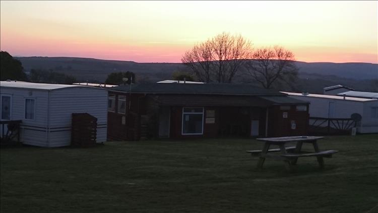 An orange sky over the distance hills behind the static caravans and toilet block at the campsite