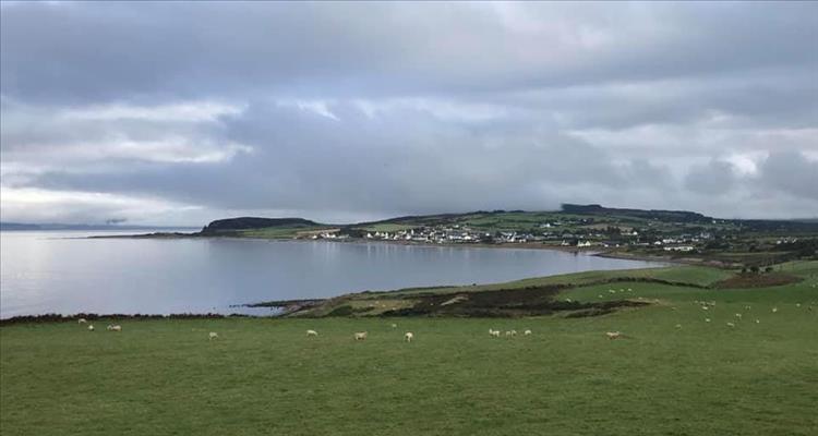 Blackwaterfoot Arron, looking over low fields and the calm waters lies a small town
