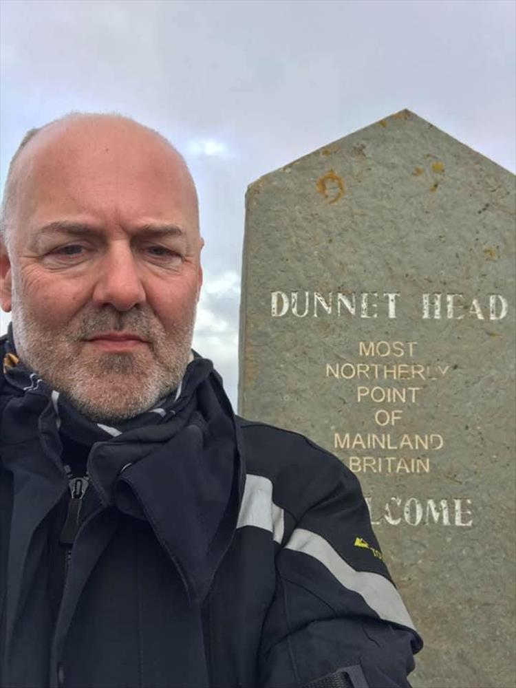 Andy stands by the stone sign telling Dunnet Head is the most northerly point of the mainland