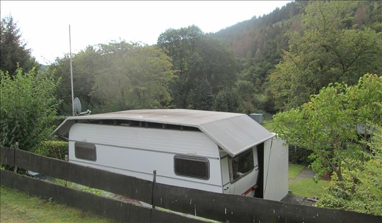 A caravan with additional DIY roof, awning, sheds and outbuildings at CampingPlatz Kohl