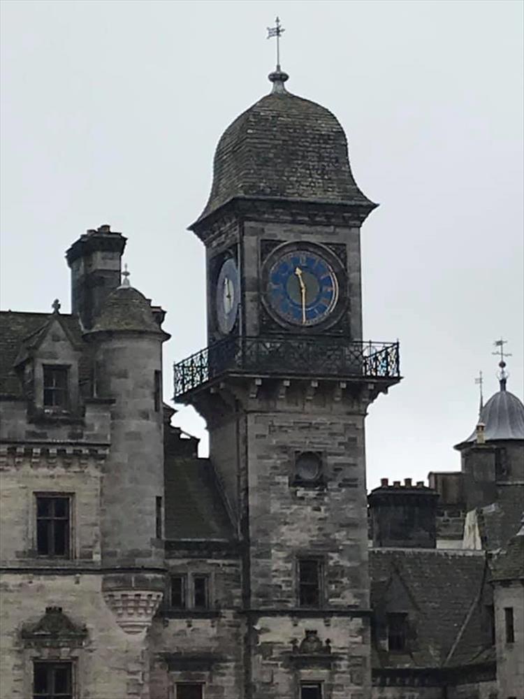 The clock is atop a square tower with blue face and golden fingers