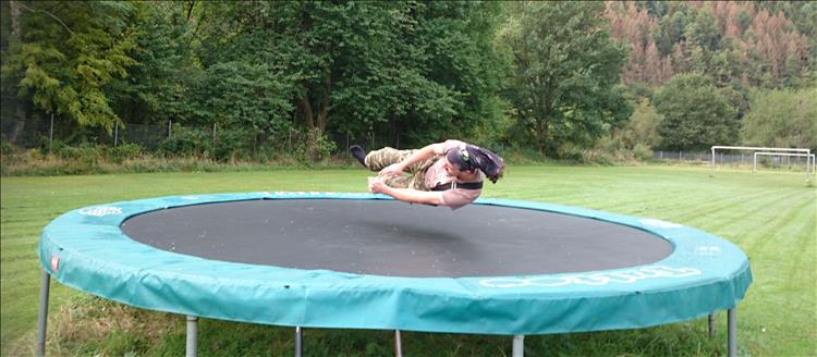 Ren is captured mid air looking like he's hovering above the large round trampoline