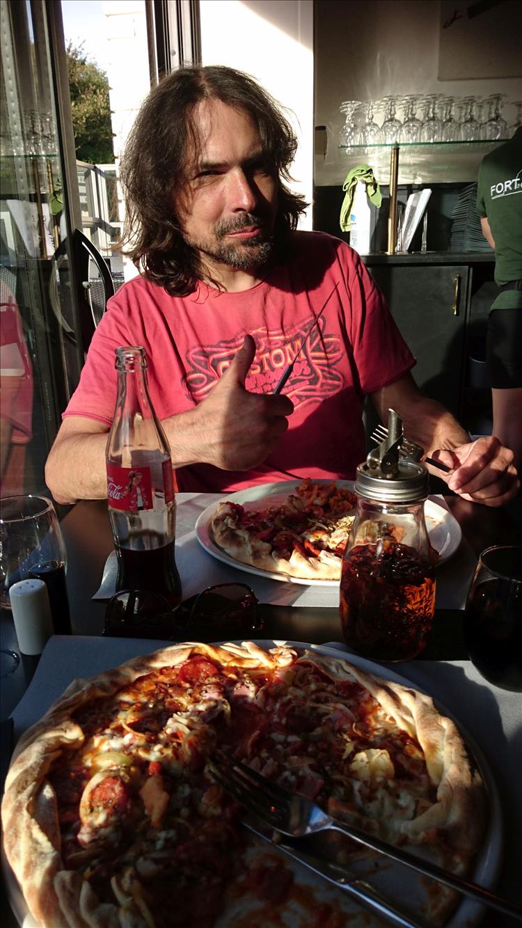 Ren eating pizza and giving a thumbs up at the restaurant in Ambleteuse
