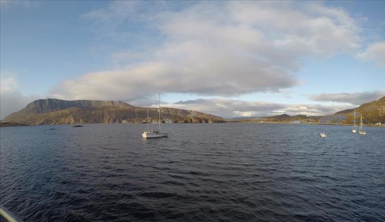 A large sea loch with a few small boats at moor and the angular highland mountains