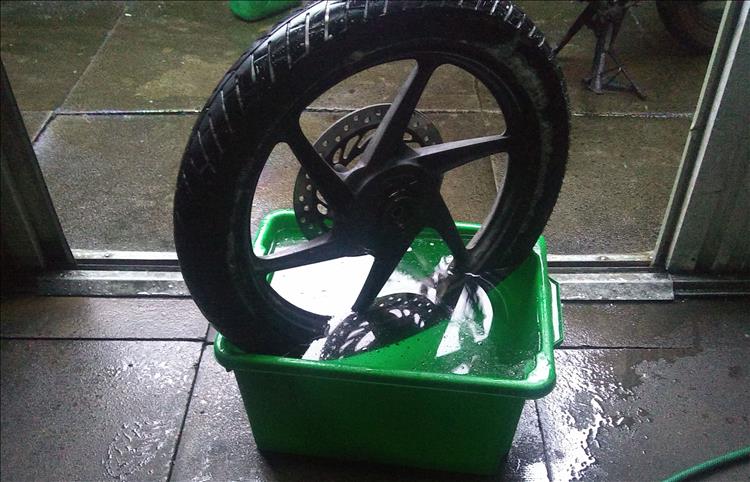 The front wheel off Ren's 125 partially submerged in a tub of water to look for leaks