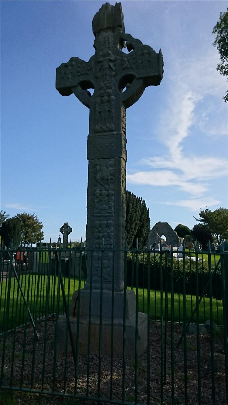 A tall stone cross with the celtic circle. Carved into the stone are well worn biblical scenes