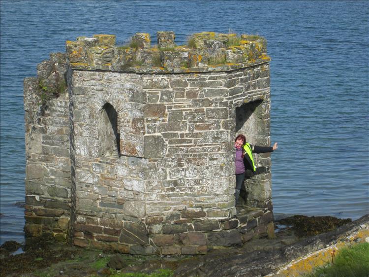 Sharon leans out of a small stumpy tower in the harbour at Ardglass, Northern Ireland