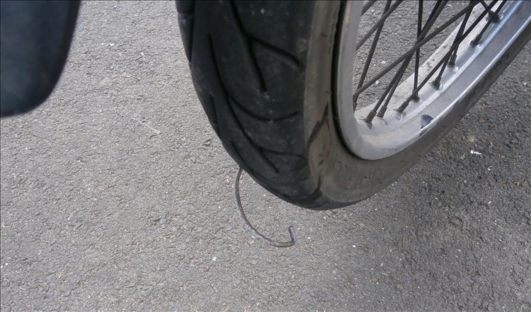 A normal motorcycle tyre with the thick heavy gauge wire of a bucket handle sticking into it