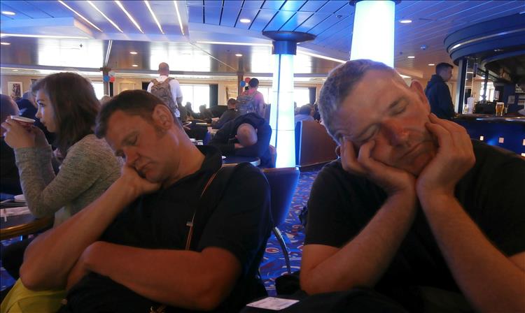 2 middle chaps sleeping on the seat of the cafe on the ferry