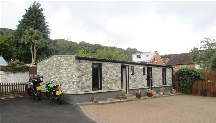 The chalet in the garden in Belfast. A small stone clad building with doors and windows