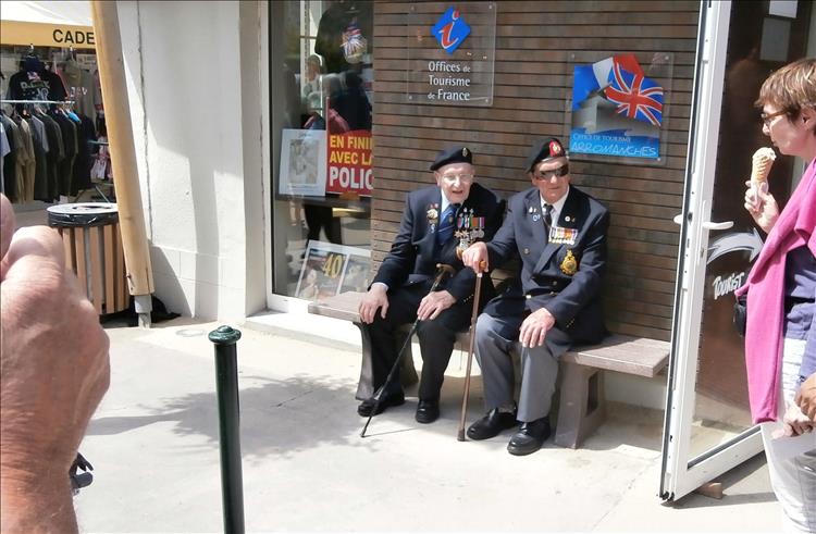 2 aged veterans with medals on their jackets in the busy town centre