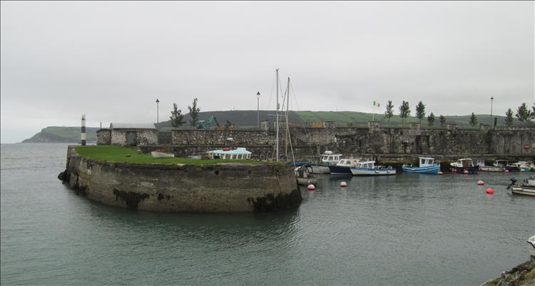 The walls of Glenclosy's harbour are this, strong and solid, protecting a cluster of small boats