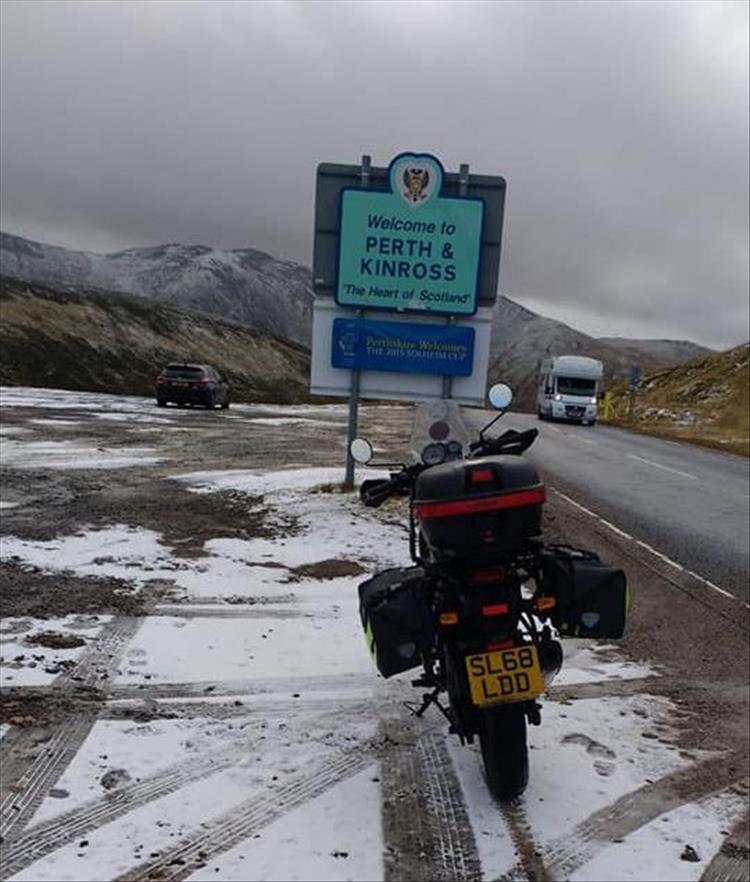 Steve's bike on a lightly snow covered layby atop a hill in Scotland, looking very bleak