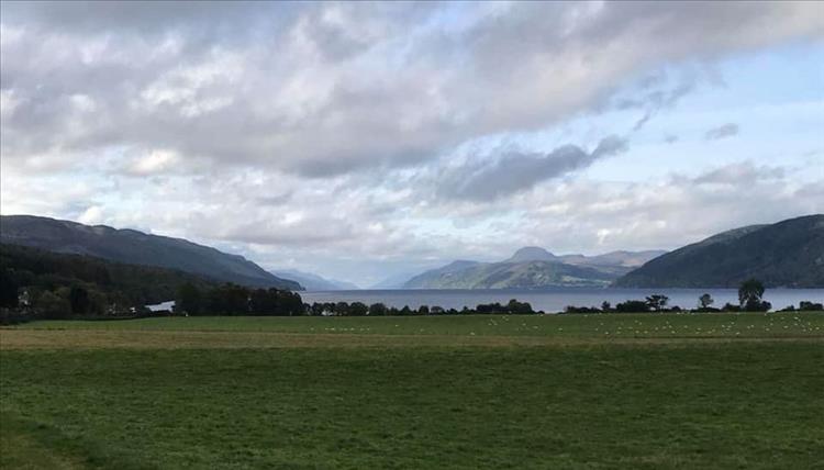 A field, then Loch Ness with the vast mountains in the distance