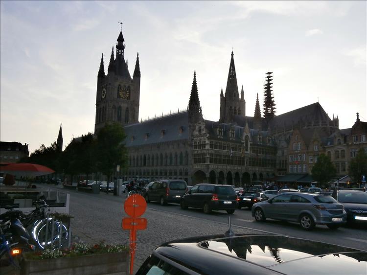 A large ornate church and cars parked in the town square at Ypres