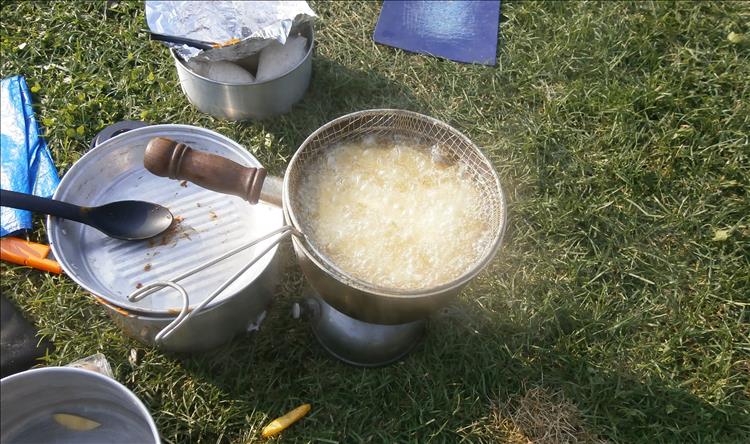 One of the camping pans with boiling oil cooking chips on the camping stove