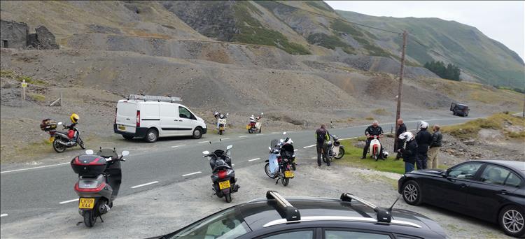 The various machines are parked and the riders chat under the vast shale hillside in wales