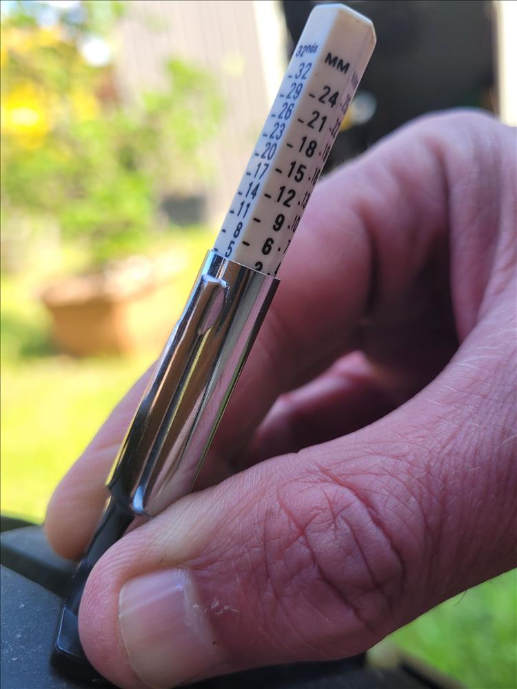 Tyre tread depth gauge showing 5mm of tread on a front motorcycle tyre
