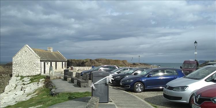 A small low house and cars at the car park in Ballintoy