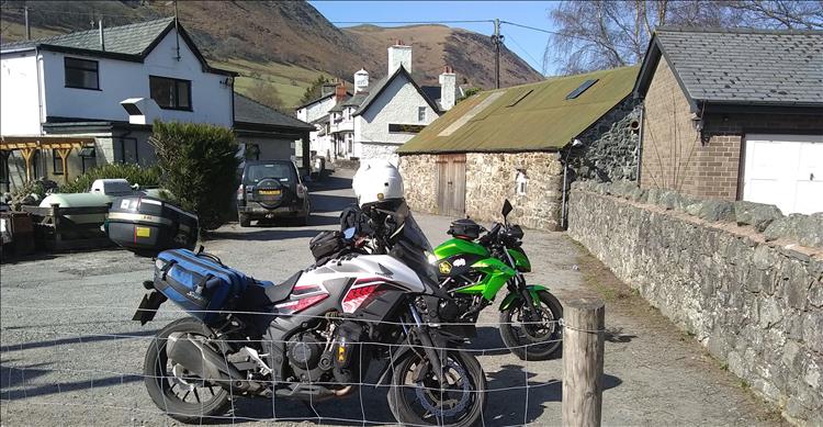 The 2 motorcycles on the car park behind the pub, towering hills behind