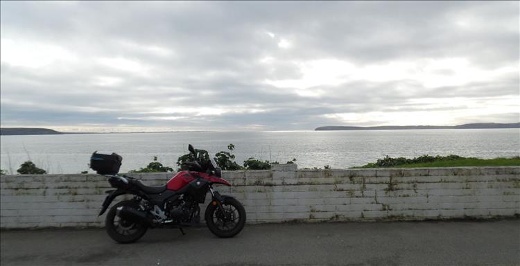 Nigel's DL250 V-Strom with a broad calm bay at Duncannon