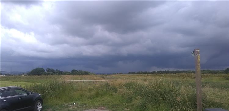 Dark heavy clouds bring rain and thunder looking over a distant horizon in Lancashire
