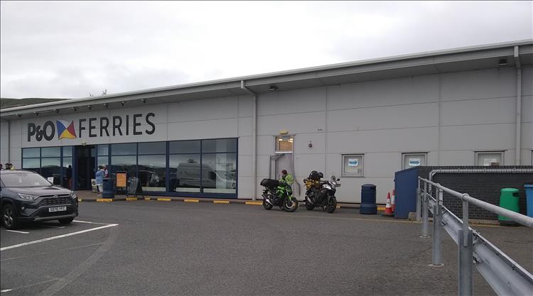 A long grey building emblazoned with the P&O logo, the 2 motorcycles parked outside