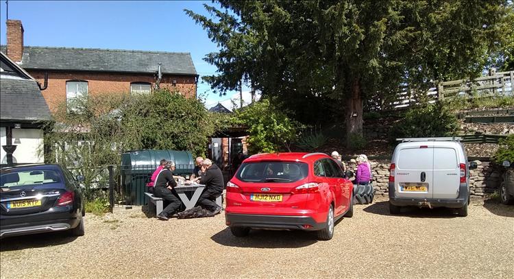 People sat at tables out in the sun around the back of the pub in Weobley