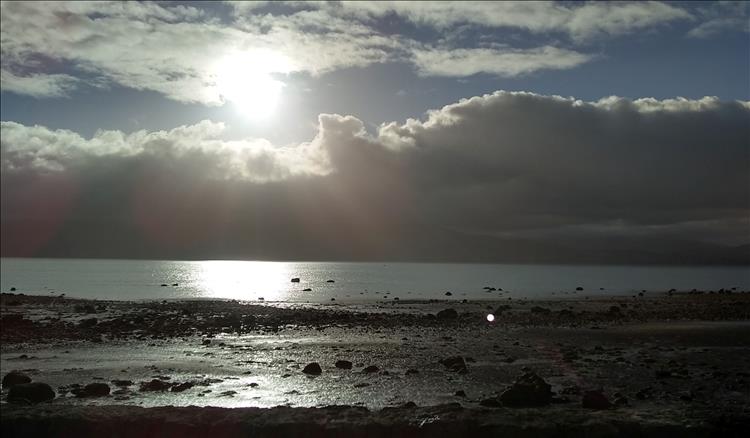 Bright sun and light clouds, the shore and the waters. An atmospheric image across to Wales
