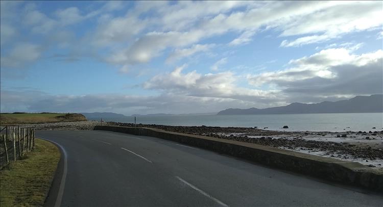 Looking down the road we see the waters of the strait and hazy snowdonian mountains