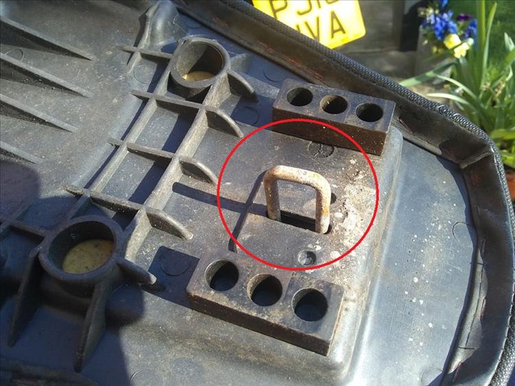 The metal square loop under the seat that form the latch