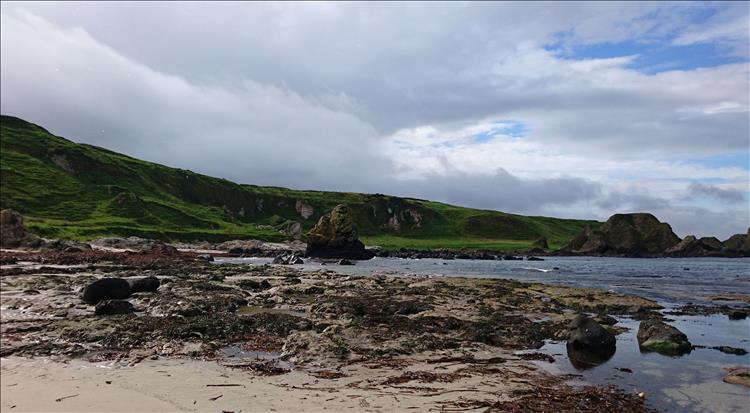 Rocks, sand, cliffs, green hills on a beach in Northern Ireland