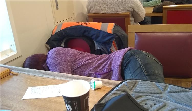 We see a bit of Sharon behind a table, lying on 2 regular dining chairs having a nap.